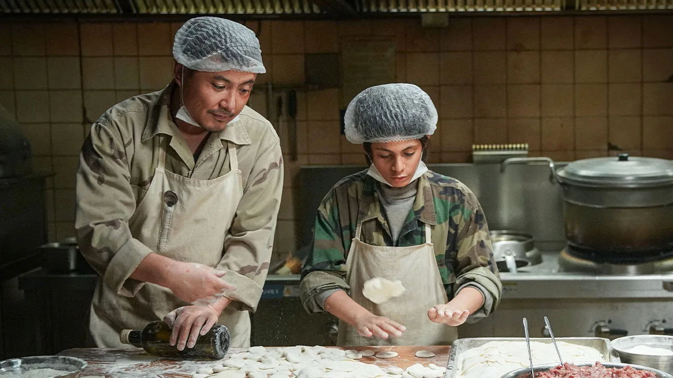 徐福和同伴戴着发网，在厨房里一起准备面食。
